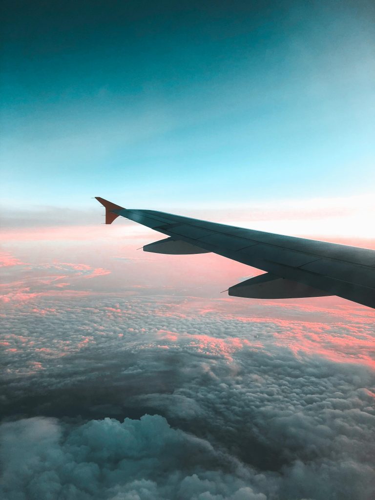 Dramatic view of an airplane wing over a colorful sunset cloudscape, capturing the essence of air travel.